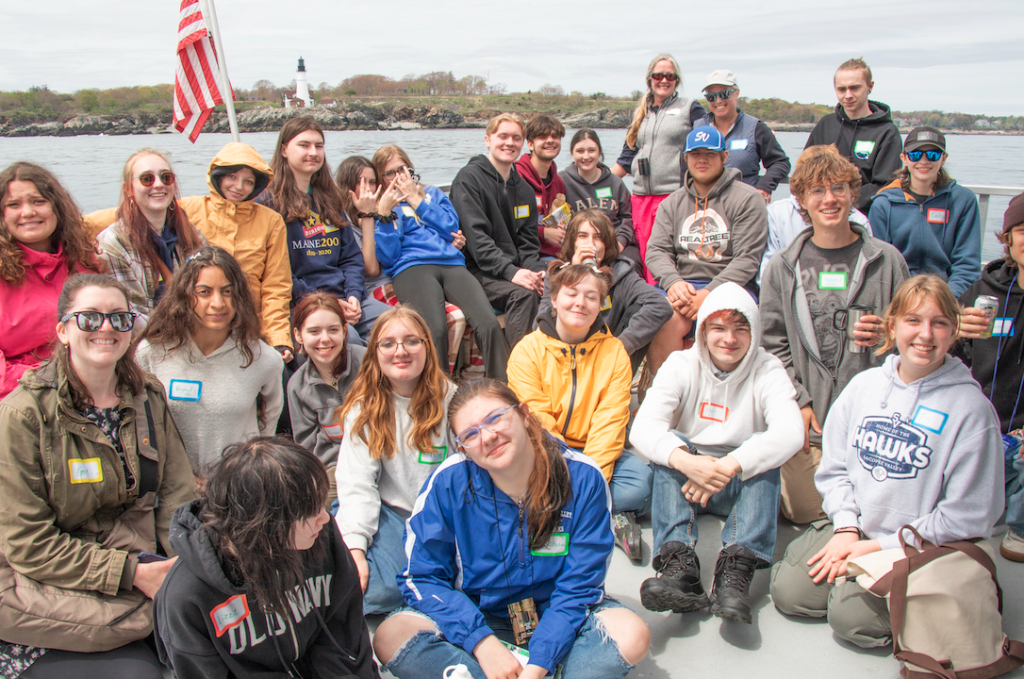 Students sit on a boat and pose for the camera.